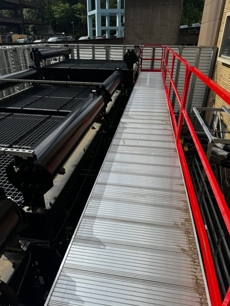 AdaptaStep elevated industrial catwalk platform with red guardrails.